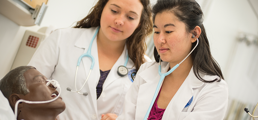 Nursing students attend to a manequin 